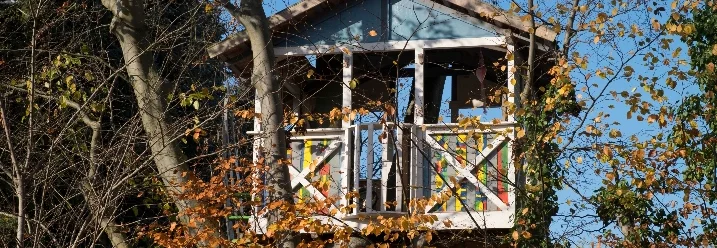 Ein buntes Baumhaus zwischen Bäumen im Herbst.